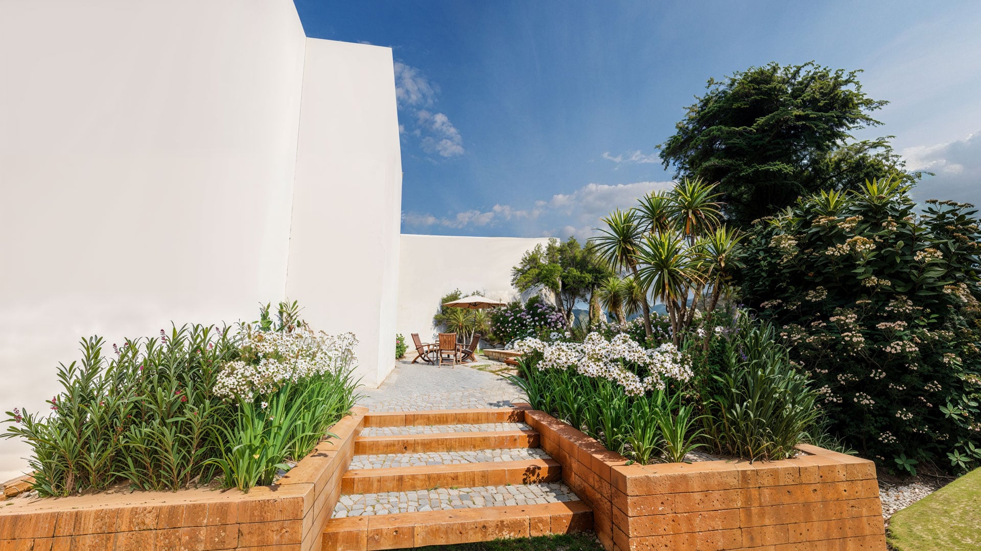 Terrasse moderne avec escalier en bois, fleurs blanches et mobilier de jardin contemporain.