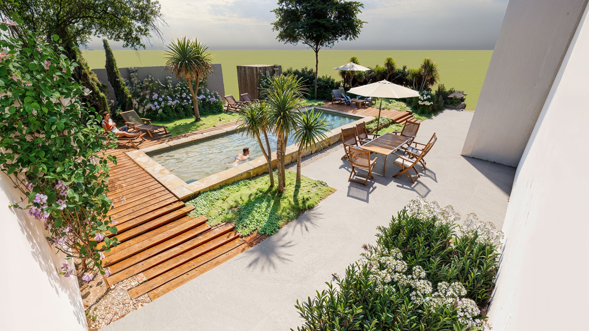Jardin luxueux avec piscine, terrasses en bois et mobilier élégant pour une séance de détente ensoleillée.