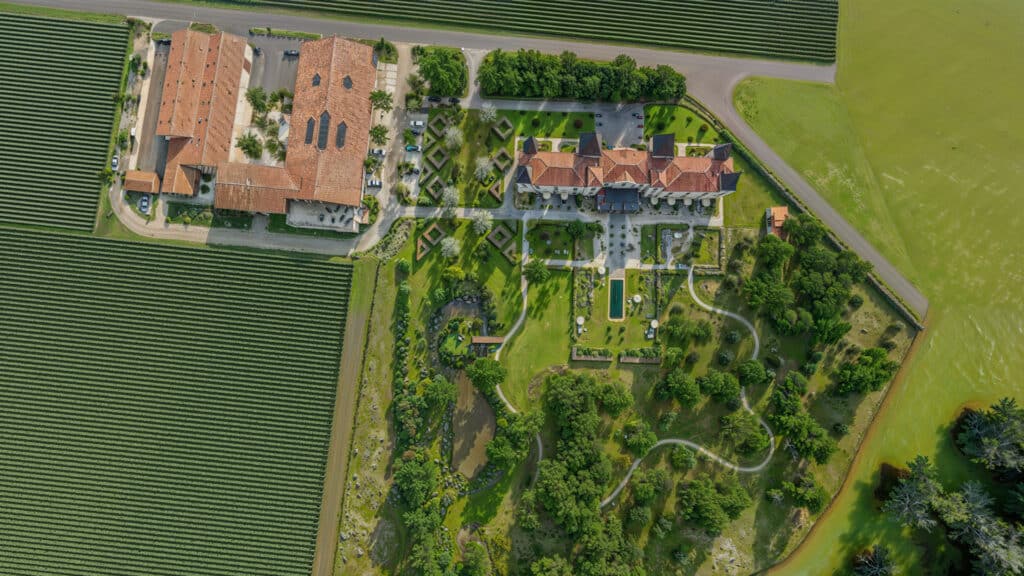 Domaine de prestige et jardins ornementaux vus du ciel Vue aérienne d'un domaine de prestige avec toits de tuiles, jardins ornementaux et vastes champs agricoles.