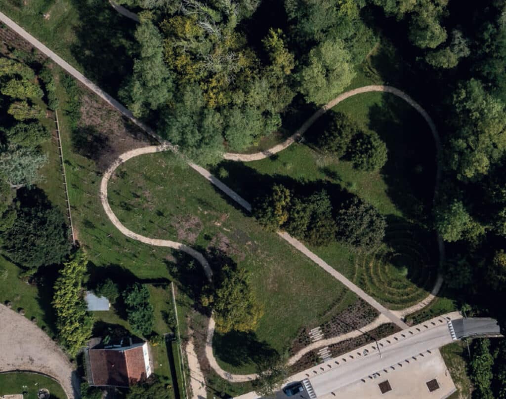 Aménagement Paysager de Parc : Sentiers et Labyrinthe Vue aérienne d'un parc avec sentiers sinueux, labyrinthe végétal et boisement dense.