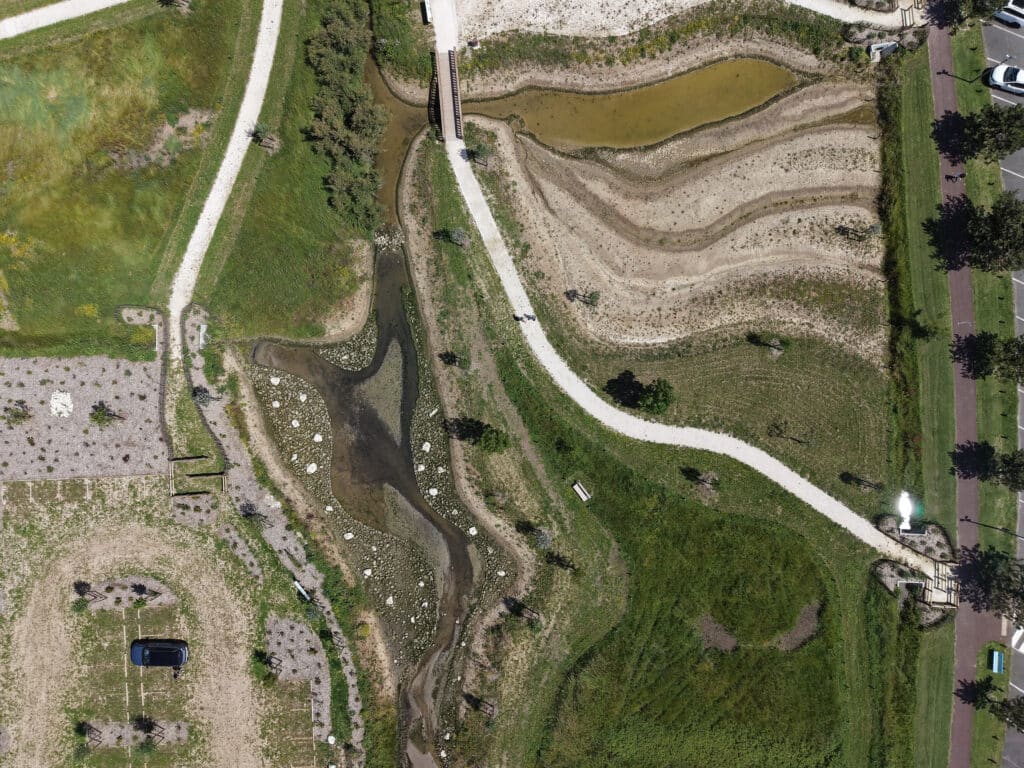 Aménagement paysager aérien : parc, sentiers et ruisseau Vue aérienne d'un parc paysager : sentiers, ruisseau rocailleux, pont en bois et aménagement en terrasses.