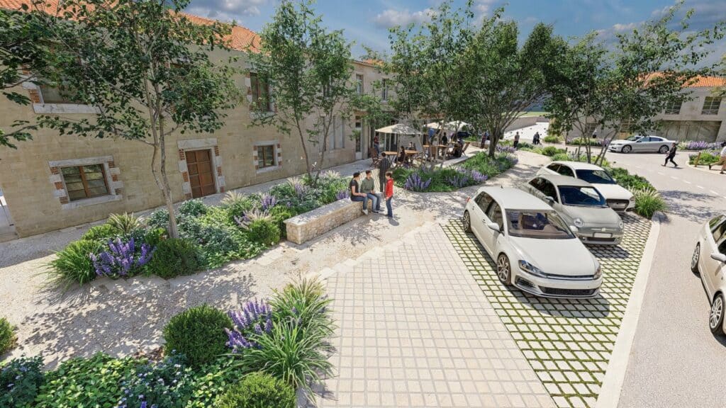 Aménagement paysager et parking en pavés drainants Cour paysagère animée, bâtiments en pierre, fleurs et parking en pavés drainants.