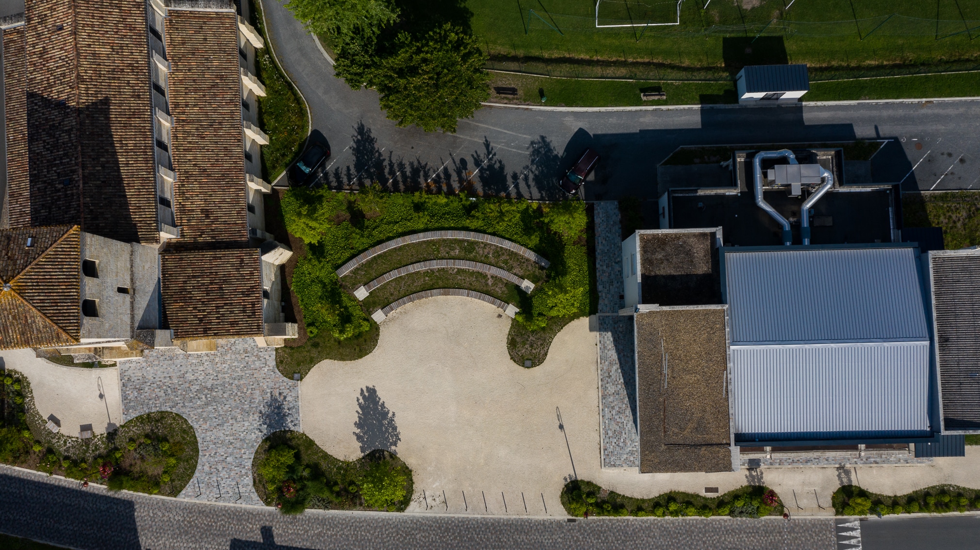Place urbaine avec gradins en bois et pavés vue du ciel entre église et bâtiment moderne.