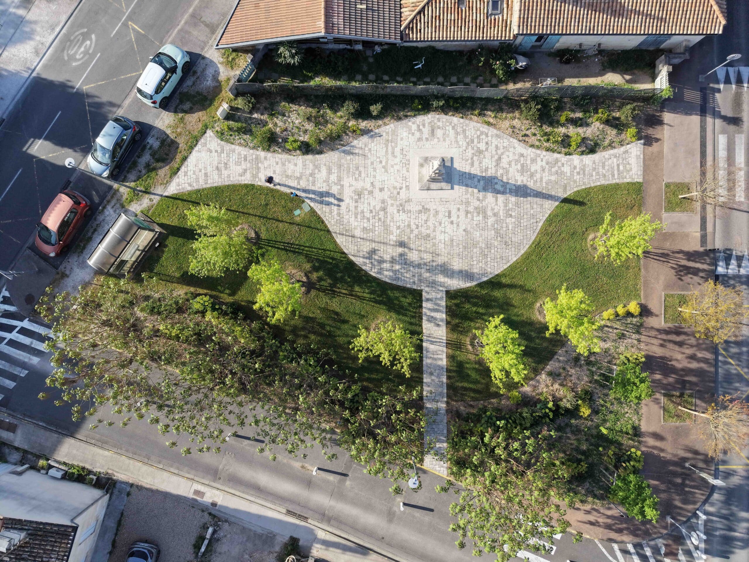 Place urbaine circulaire avec monument central et espaces verts vus du ciel.
